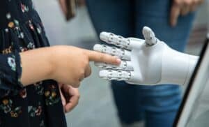 Human hand reaching toward a robotic hand, representing human connection and the growing role of AI technology